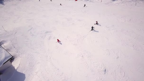 Skifahrer, die am Wintertag im Hochgebirge die Skipiste hinunter fahren, Luftaufnahme — Stockvideo
