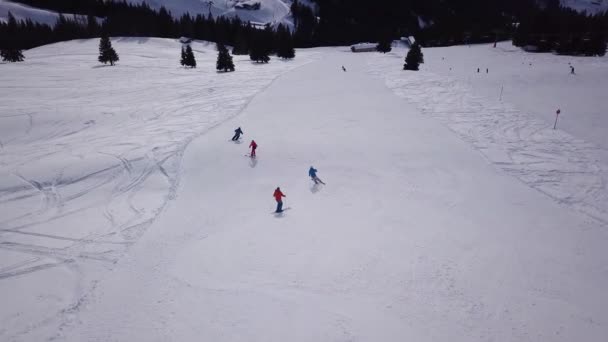 Légi kilátás síközpont az emberek snowboard le a hegyről. Készletfelvétel. Repülő át a sí vagy snowboard pálya fehér hó körül sűrű erdő téli szezonban, utazás és a sport — Stock videók