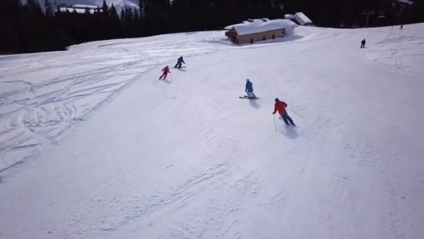 Widok z lotu ptaka na ośrodek narciarski z ludźmi na snowboardzie w dół wzgórza. Materiał filmowy. Latanie nad torem narciarskim lub snowboardowym na białym śniegu otoczonym gęstym lasem w sezonie zimowym, podróże i sport — Wideo stockowe