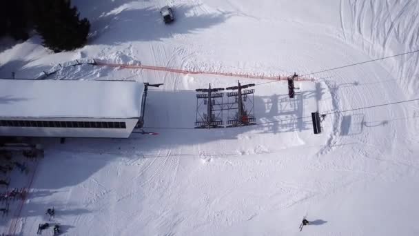 滑雪座椅升降机的空中俯视图.Ski度假村的交通人员很少。雪地滑雪斜坡上的滑雪者和滑雪者。无人机飞过小木屋和人群电梯电缆冬季春山 — 图库视频影像