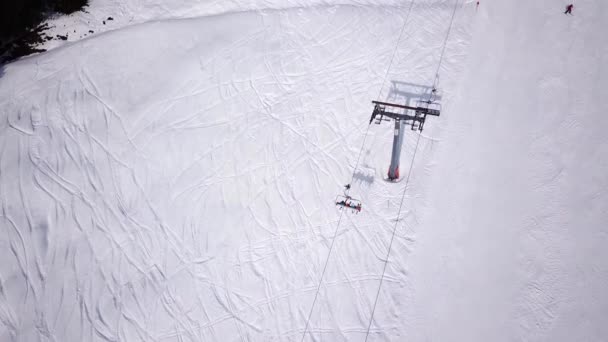 Luftaufnahme des Sesselliftes. Wenige Leute für Transport im Skigebiet. Skifahrer und Snowboarder auf der verschneiten Skipiste. Drohne fliegt über Kabine und Menschenmenge Seilbahn Winter Spring Mountain — Stockvideo