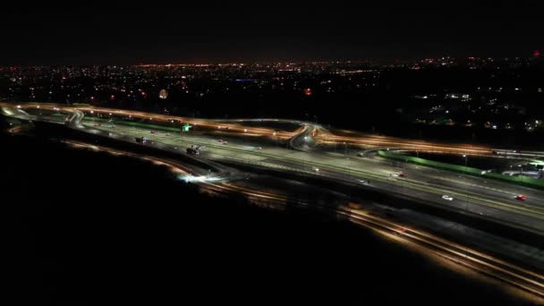 Caminos nocturnos de arriba abajo con coches que conducen vista aérea. Paisaje urbano nocturno con rascacielos modernos. Majestuoso paisaje urbano iluminado por faroles de neón luces con carretera de tráfico. Paisaje de vehículos cinematográficos — Vídeos de Stock