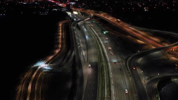 Gece şehir yollarının tepesinde hava manzaralı arabalar var. Geceleri modern gökdelenleri olan şehir manzarası. Görkemli şehir manzarası trafik otobanlı neon fenerlerle aydınlatılıyor. Sinematik araç manzarası — Stok video