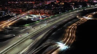 Gece şehir yollarının tepesinde hava manzaralı arabalar var. Geceleri modern gökdelenleri olan şehir manzarası. Görkemli şehir manzarası trafik otobanlı neon fenerlerle aydınlatılıyor. Sinematik araç manzarası