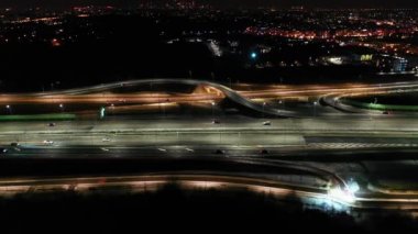 Gece şehir yollarının tepesinde hava manzaralı arabalar var. Geceleri modern gökdelenleri olan şehir manzarası. Görkemli şehir manzarası trafik otobanlı neon fenerlerle aydınlatılıyor. Sinematik araç manzarası