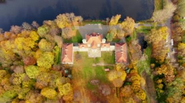 Güneşin doğuşunda Forrest Gölü 'nün üzerinde sis bulutu üzerinde manzara uçuşu, 4K görüntü. Sabahın erken saatlerinde renkli sonbahar ağaçları. Efsanevi ihtişam ilham kaynağı. Palac Bielinskich w Otwocku Wielkim