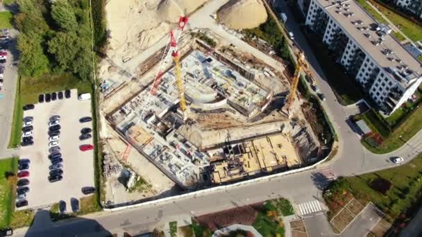 Vuelo aéreo sobre un sitio de desarrollo de nuevas construcciones con grúas de torre alta Building Real Estate. Se emplean trabajadores de maquinaria pesada y construcción. Vista de arriba hacia abajo en los contratistas en sombreros de seguridad. — Vídeos de Stock