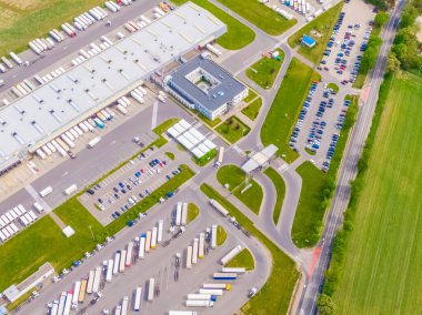 Deposu olan bir lojistik parkının hava görüntüsü, yükleme merkezi ve yükleme / boşaltma için rampalarda bekleyen bir sürü kargo karavanı olan kamyonlar.