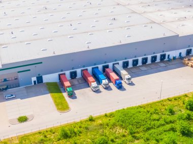 Deposu olan bir lojistik parkının hava görüntüsü, yükleme merkezi ve yükleme / boşaltma için rampalarda bekleyen bir sürü kargo karavanı olan kamyonlar.