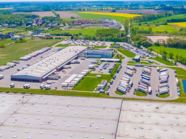 Deposu olan bir lojistik parkının hava görüntüsü, yükleme merkezi ve yükleme / boşaltma için rampalarda bekleyen bir sürü kargo karavanı olan kamyonlar.