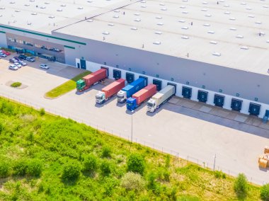 Deposu olan bir lojistik parkının hava görüntüsü, yükleme merkezi ve yükleme / boşaltma için rampalarda bekleyen bir sürü kargo karavanı olan kamyonlar.