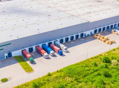 Aerial view of a logistics park with warehouse, loading hub and many semi trucks with cargo trailers standing at the ramps for load/unload