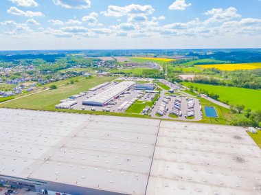 Aerial view of a logistics park with warehouse, loading hub and many semi trucks with cargo trailers standing at the ramps for load/unload