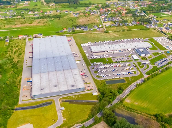 Deposu olan bir lojistik parkının hava görüntüsü, yükleme merkezi ve yükleme / boşaltma için rampalarda bekleyen bir sürü kargo karavanı olan kamyonlar.