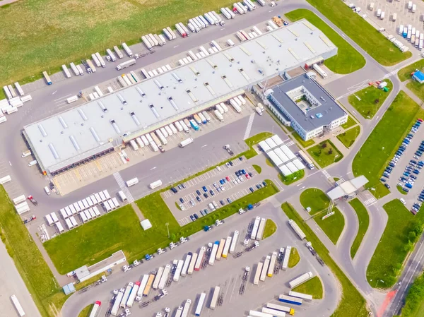 Deposu olan bir lojistik parkının hava görüntüsü, yükleme merkezi ve yükleme / boşaltma için rampalarda bekleyen bir sürü kargo karavanı olan kamyonlar.
