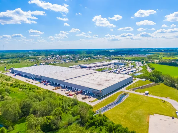 Deposu olan bir lojistik parkının hava görüntüsü, yükleme merkezi ve yükleme / boşaltma için rampalarda bekleyen bir sürü kargo karavanı olan kamyonlar.