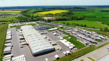 Aerial view of a semi trucks with cargo trailers standing on warehouses ramps for loading/unloading goods on the big logistics park with loading hub