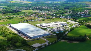 Kargo karavanlı yarı kamyon bir lojistik parkının deposu boyunca bir otoparkta seyahat ediyor. Aşağıdaki hava çekimi