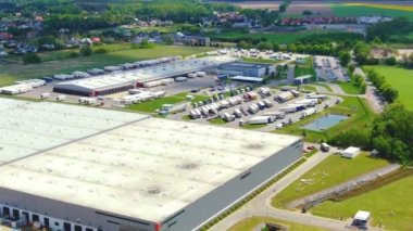 Yarı römorklu kamyonlar lojistik parkının otoparkında durup gün batımında depo rampalarında yükleme ve boşaltma için bekliyorlar. Hava görünümü