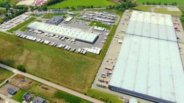 Yarı römorklu kamyonlar lojistik parkının otoparkında durup gün batımında depo rampalarında yükleme ve boşaltma için bekliyorlar. Hava görünümü