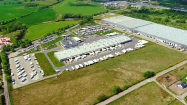 Yarı römorklu kamyonlar lojistik parkının otoparkında durup gün batımında depo rampalarında yükleme ve boşaltma için bekliyorlar. Hava görünümü