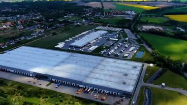 Deposu olan bir lojistik parkı. Yükleme merkezi. Gün batımında malları yüklemek ve boşaltmak için rampalarda duran yarı karavan kamyonları. Hava hiper hızı (hareket süresi aşımı)).