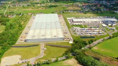 Yarı römorklu kamyonlar lojistik parkının otoparkında durup gün batımında depo rampalarında yükleme ve boşaltma için bekliyorlar. Hava görünümü