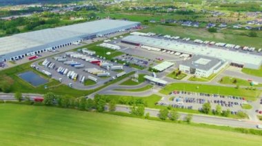 Yarı römorklu kamyonlar lojistik parkının otoparkında durup gün batımında depo rampalarında yükleme ve boşaltma için bekliyorlar. Hava görünümü