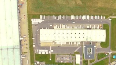Aerial top down view of the big logistics park with warehouses, loading hub and a lot of semi trucks with cargo trailers awaiting for loading/unloading goods on ramps