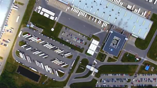 Aerial top down view of the big logistics park with warehouses, loading hub and a lot of semi trucks with cargo trailers awaiting for loading/unloading goods on ramps — Vídeo de stock