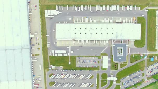Aerial top down view of the big logistics park with warehouses, loading hub and a lot of semi trucks with cargo trailers awaiting for loading/unloading goods on ramps — Vídeo de Stock