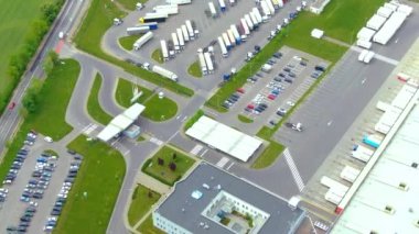 Depoları olan büyük lojistik parkının havadan aşağı görüntüsü, yükleme merkezi ve rampalarda malları yükleyip indirmeyi bekleyen kargo karavanları olan bir sürü kamyonet.