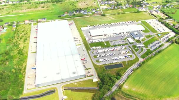 Aerial top down view of the big logistics park with warehouses, loading hub and a lot of semi trucks with cargo trailers awaiting for loading/unloading goods on ramps — Αρχείο Βίντεο