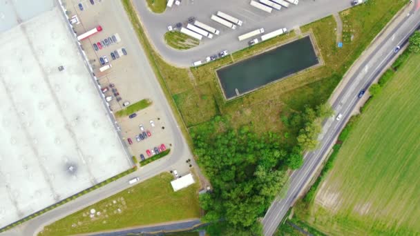 Edificios de centro logístico, almacenes cerca de la carretera, proceso de estacionamiento de camiones, vista desde la altura, un gran número de camiones en el estacionamiento cerca del almacén. — Vídeo de stock