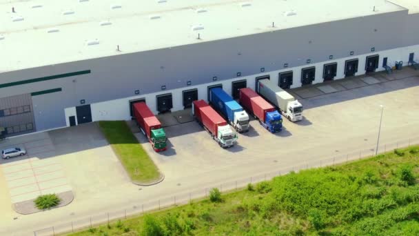 Edificios de centro logístico, almacenes cerca de la carretera, proceso de estacionamiento de camiones, vista desde la altura, un gran número de camiones en el estacionamiento cerca del almacén. — Vídeo de stock