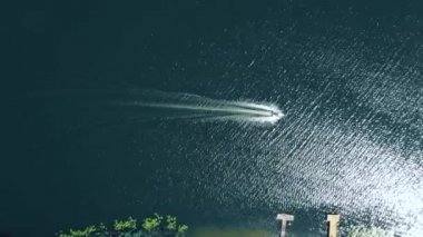 Koyu renkli lüks bir tekne, mavi suda hızlı hareket, hava manzarası. Su üstünde hareket eden pahalı lüks bir İtalyan teknesi. Tekne koyu renk ahşap, su üstünde hareket var..