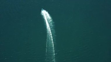 Koyu renkli lüks bir tekne, mavi suda hızlı hareket, hava manzarası. Su üstünde hareket eden pahalı lüks bir İtalyan teknesi. Tekne koyu renk ahşap, su üstünde hareket var..