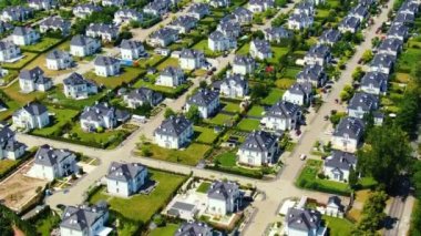 Street with new homes in spring season. Single family houses and residential construction planned community. Aerial from backyard to front exterior reveal as car drives by.