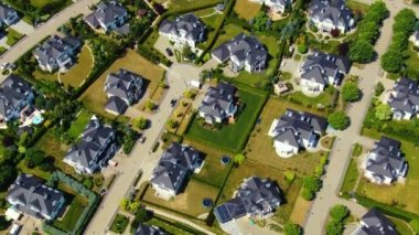 Street with new homes in spring season. Single family houses and residential construction planned community. Aerial from backyard to front exterior reveal as car drives by.