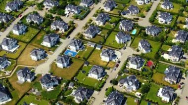 Street with new homes in spring season. Single family houses and residential construction planned community. Aerial from backyard to front exterior reveal as car drives by.