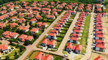 Aerial drone footage over the summer street. Modern luxury houses. Aerial flying over the residential area. Asphalt roads and sidewalks. Red roof
