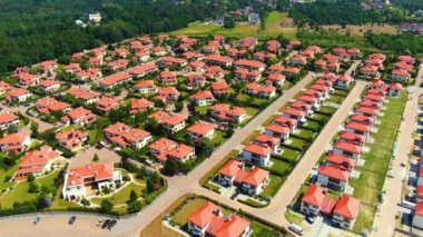 Aerial drone footage over the summer street. Modern luxury houses. Aerial flying over the residential area. Asphalt roads and sidewalks. Red roof