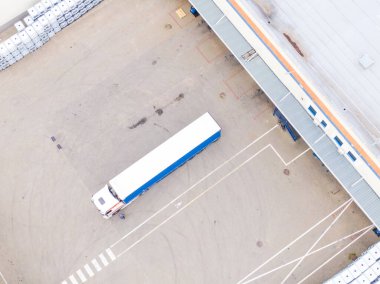 Malzeme deposunun havadan görüntüsü. Sanayi bölgesine yukarıdan lojistik merkezi teslimatı. Lojistik merkezde yüklenen kamyonların hava görüntüsü