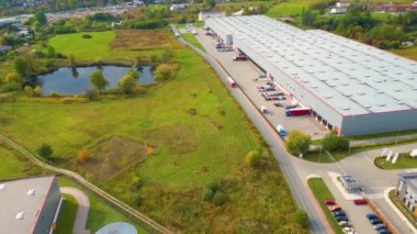 Aerial view of a semi trucks with cargo trailers standing on warehouses ramps for loading/unloading goods on the big logistics park with loading hub