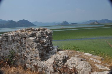 Karadağ 'daki Skadar Gölü. Doğanın ve dağların zenginliğiyle gölün açık yüzeyi. Gölde tekne turu.
