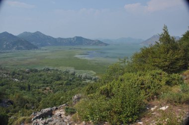 Karadağ 'daki Skadar Gölü. Doğanın ve dağların zenginliğiyle gölün açık yüzeyi. Gölde tekne turu.