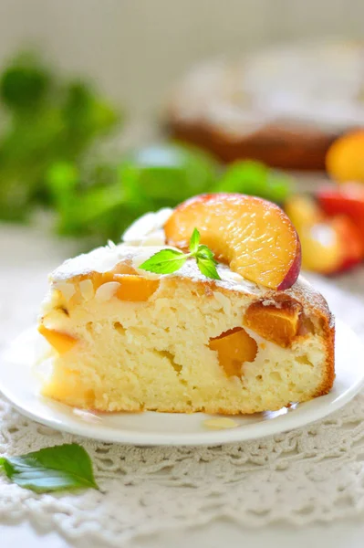 Sponge cake (slice) with peaches and a sprig of mint