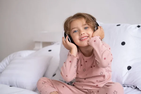 Lachend Gelukkig Klein Meisje Pyjama Met Draadloze Hoofdtelefoon Die Thuis — Stockfoto