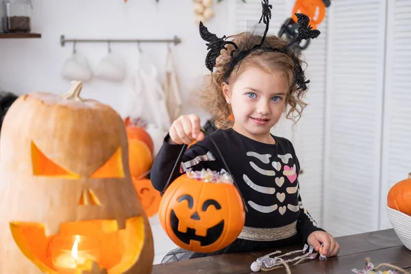Aranyos kislány jelmezben boszorkány gazdaság tök jack cukorka, szórakozás a konyhában, ünneplés Halloween — Stock Fotó