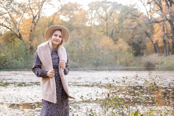 Bela jovem mulher elegante no chapéu caminha na natureza no parque de outono no outono — Fotografia de Stock